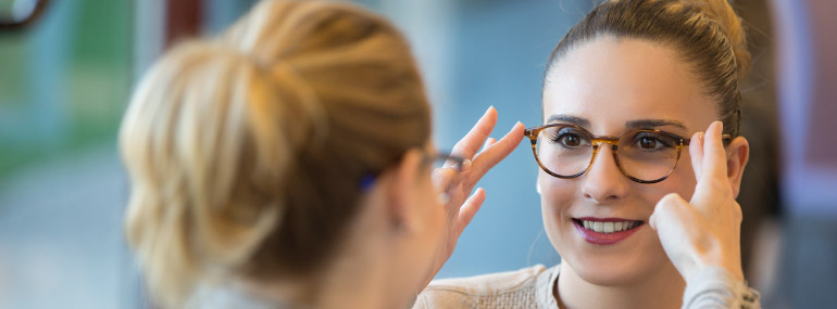 Woman fitting another woman for new glasses.