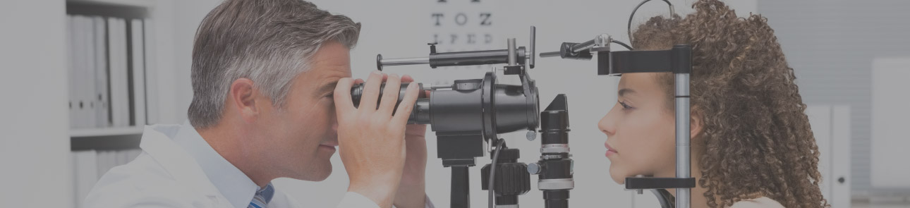 Optometrist giving a young woman an eye exam.