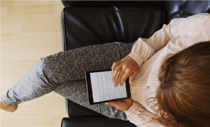 Woman works on her tablet as she waits.