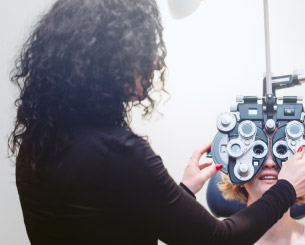 Optometrist giving an eye exam to a woman.