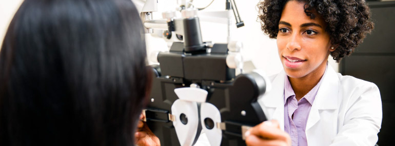Optometrist giving an eye exam to a woman.