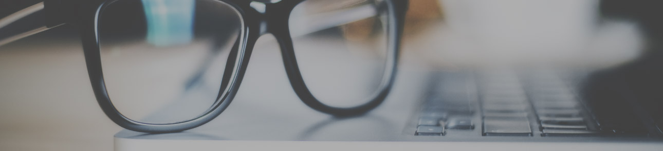 Close up of eye glasses sitting on a computer.