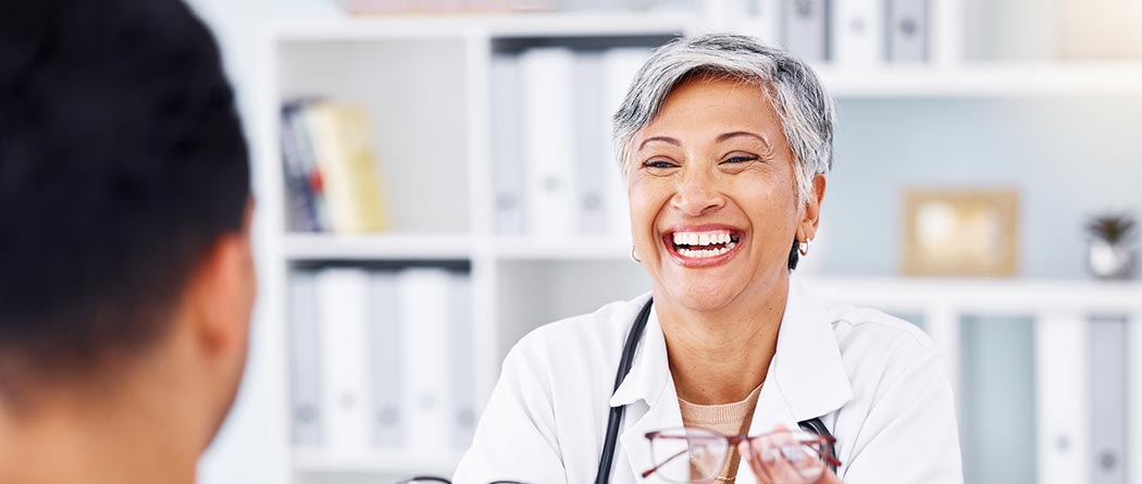 Doctor holding glasses at desk.